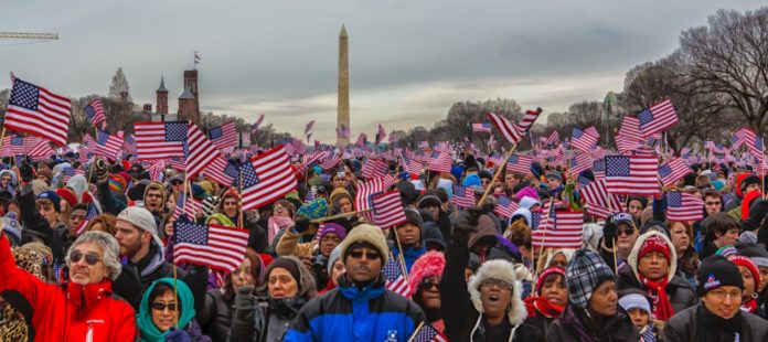 Americans waving flags in front of the washington monument